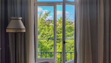 Habitación con una silla, una lámpara y vistas a un balcón con vegetación a través de un vidrio.