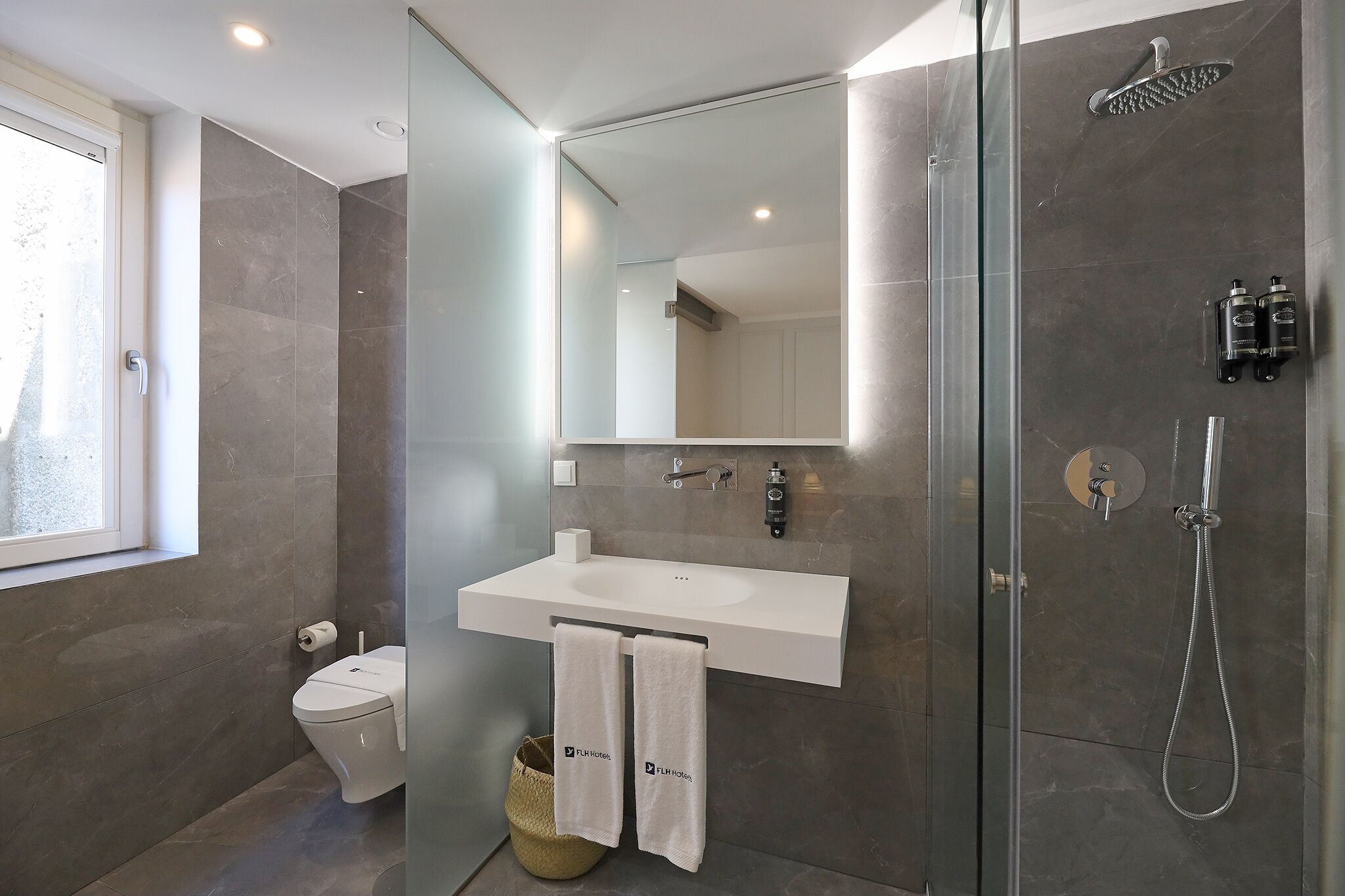 A modern bathroom with a glass shower enclosure, a white sink, and a toilet.