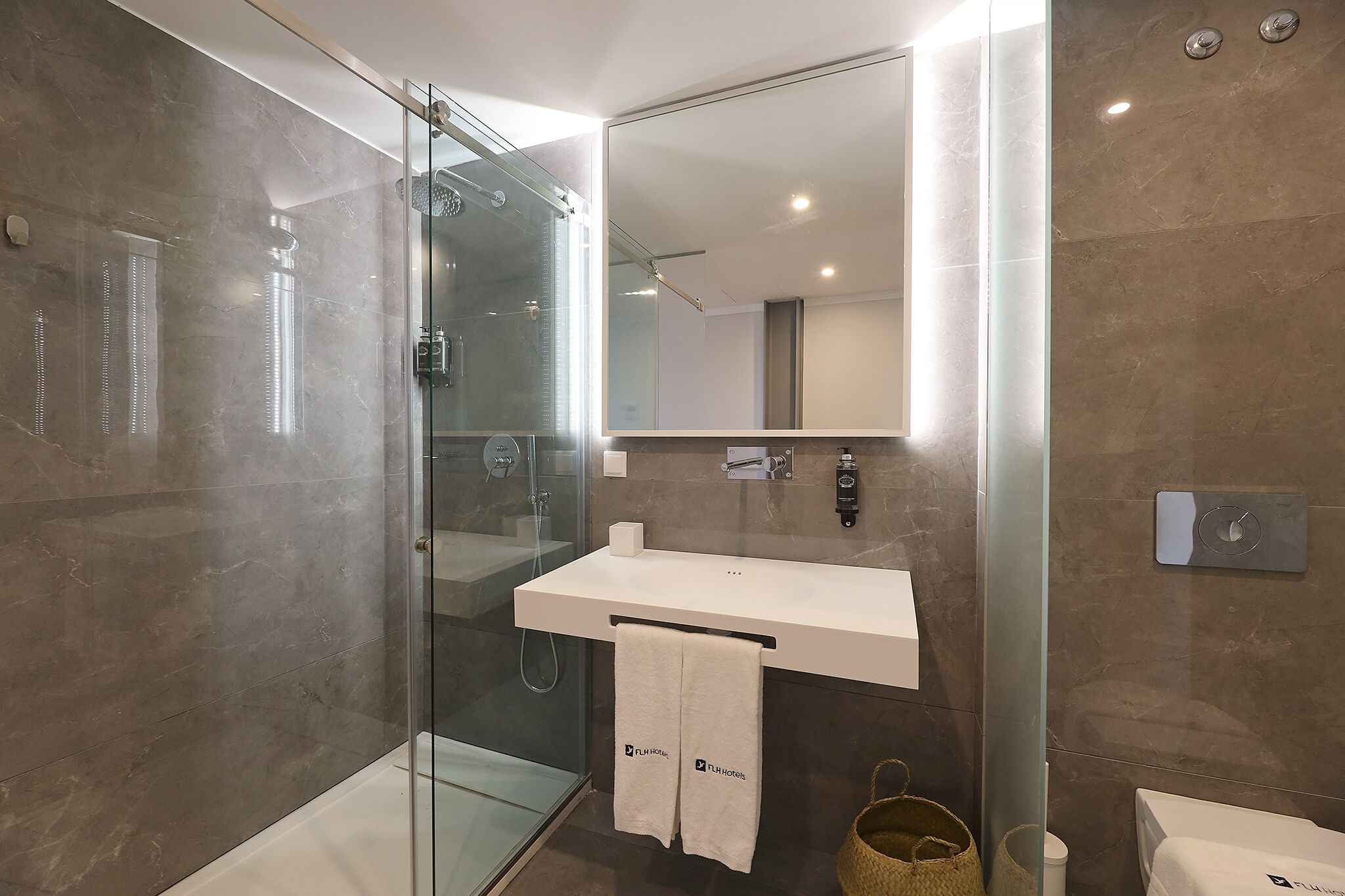 A modern bathroom with a glass-enclosed shower, a white sink, and a large mirror.