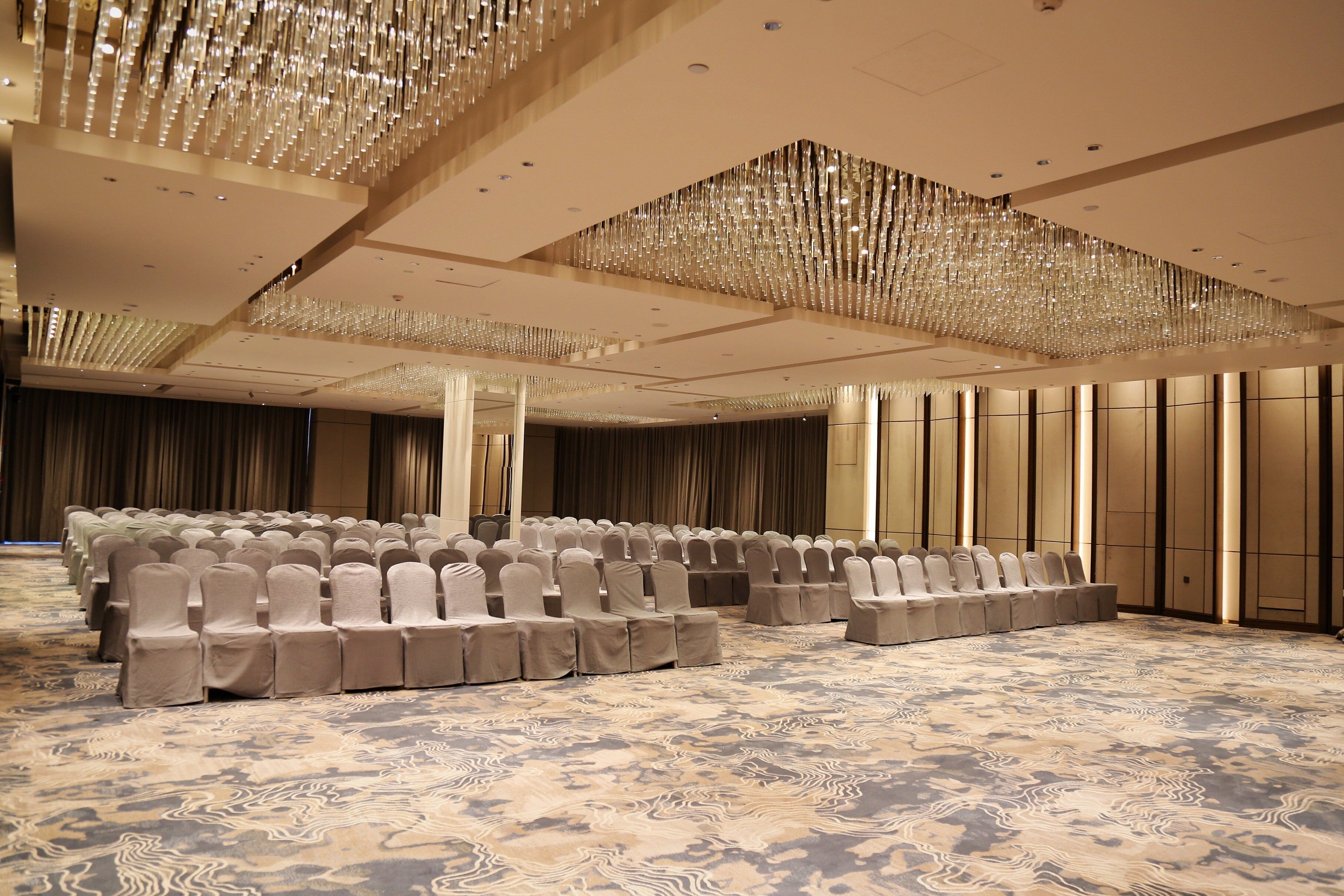 A conference room with rows of chairs, a patterned carpet, and a decorative ceiling.