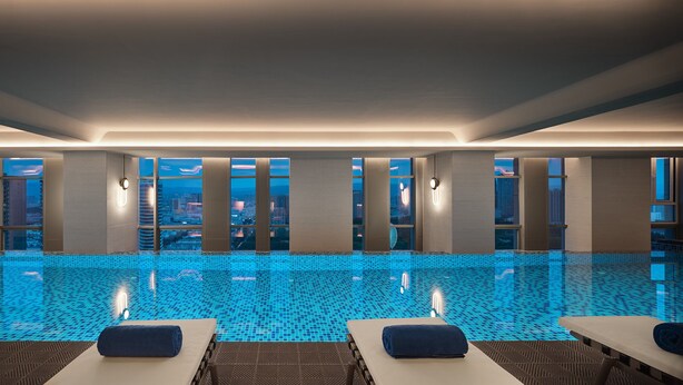 A modern indoor swimming pool with a city view, featuring multiple lounge areas and a tiled floor. - Crowne Plaza Hohhot City Center by IHG (Hohhot)