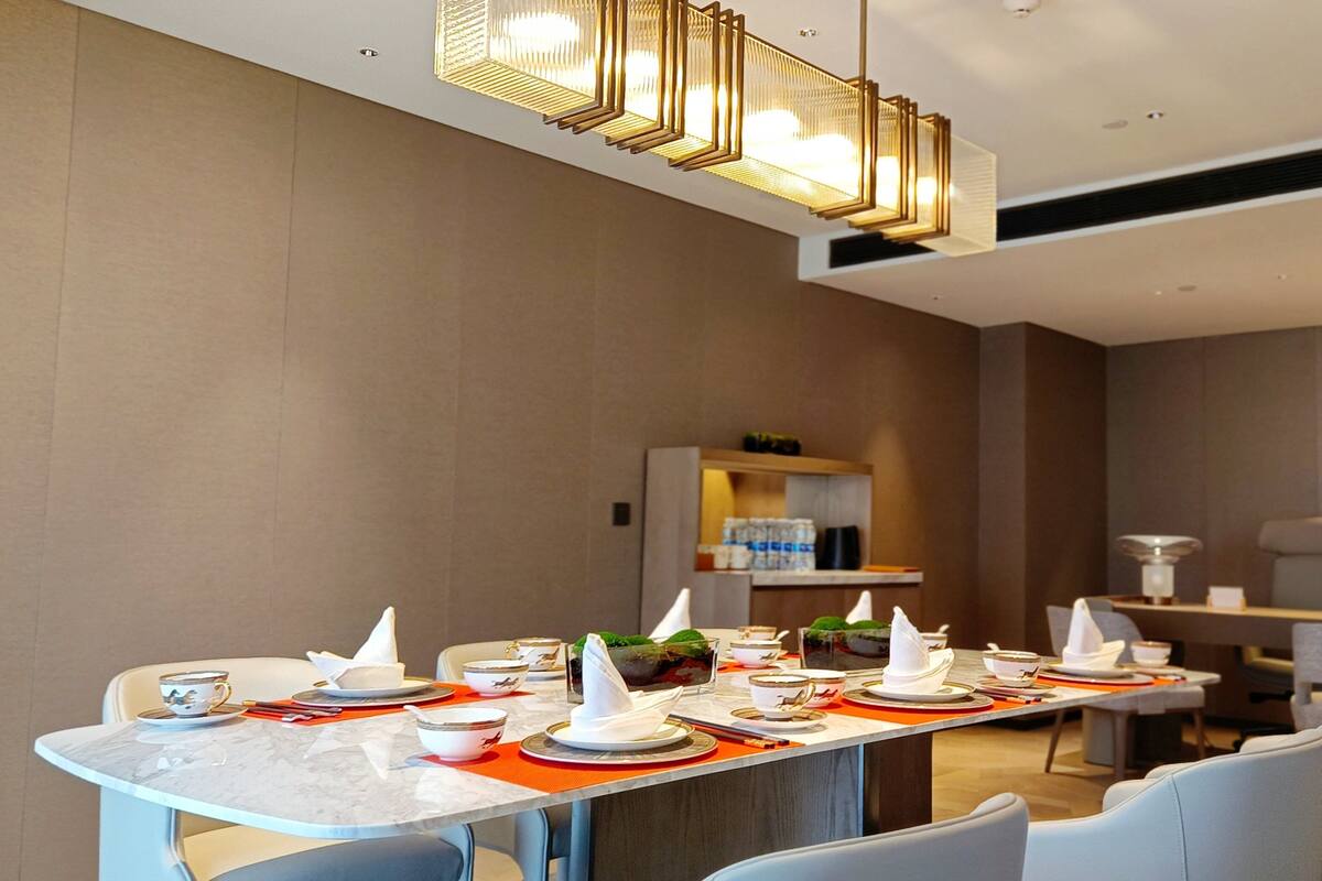 Un comedor moderno con una larga mesa dispuesta para una comida, con platos, tazones y cubiertos.