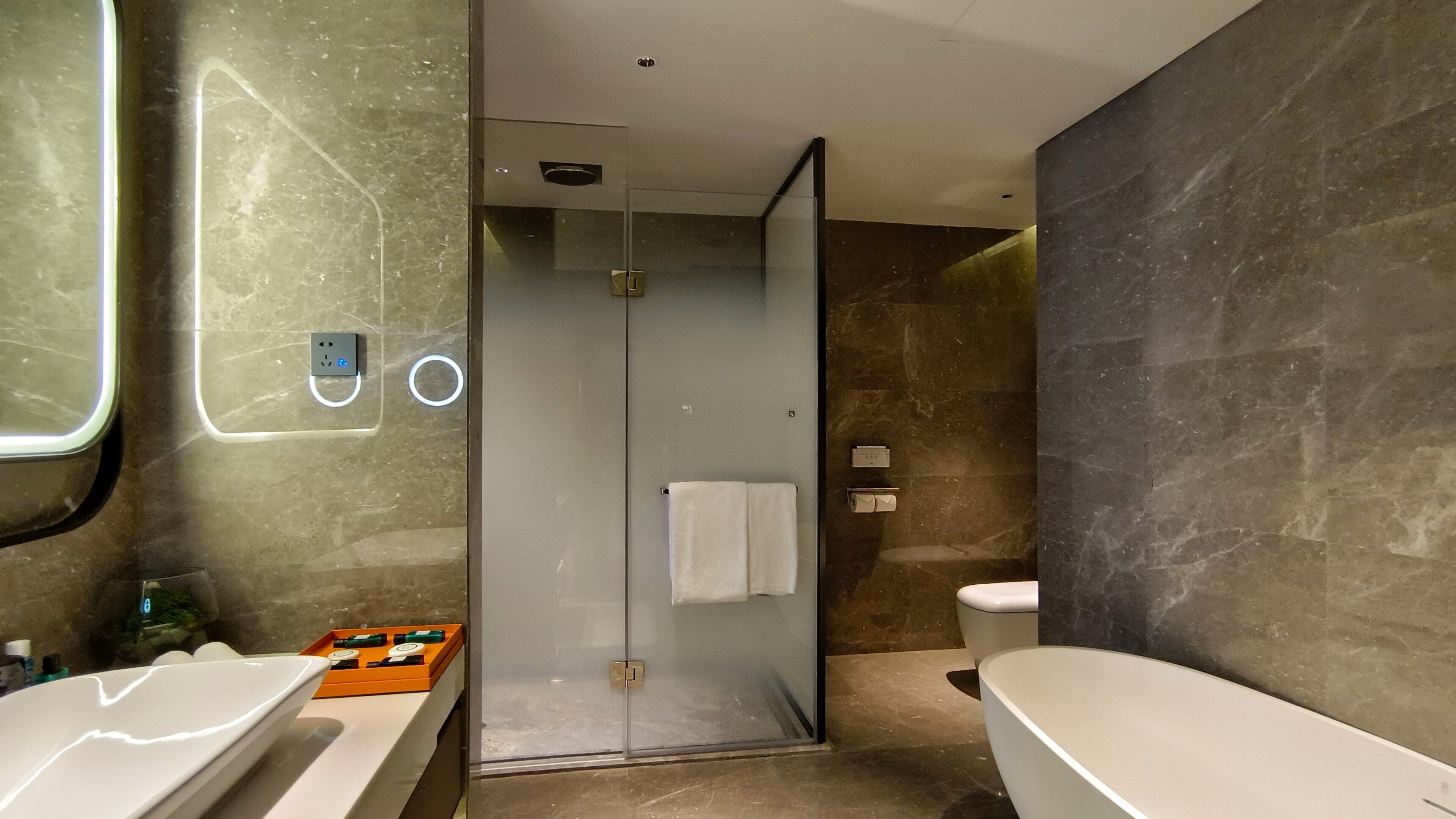 Ein modernes Badezimmer mit Duschkabine aus Glas, einer weißen Badewanne und einem großen Spiegel.