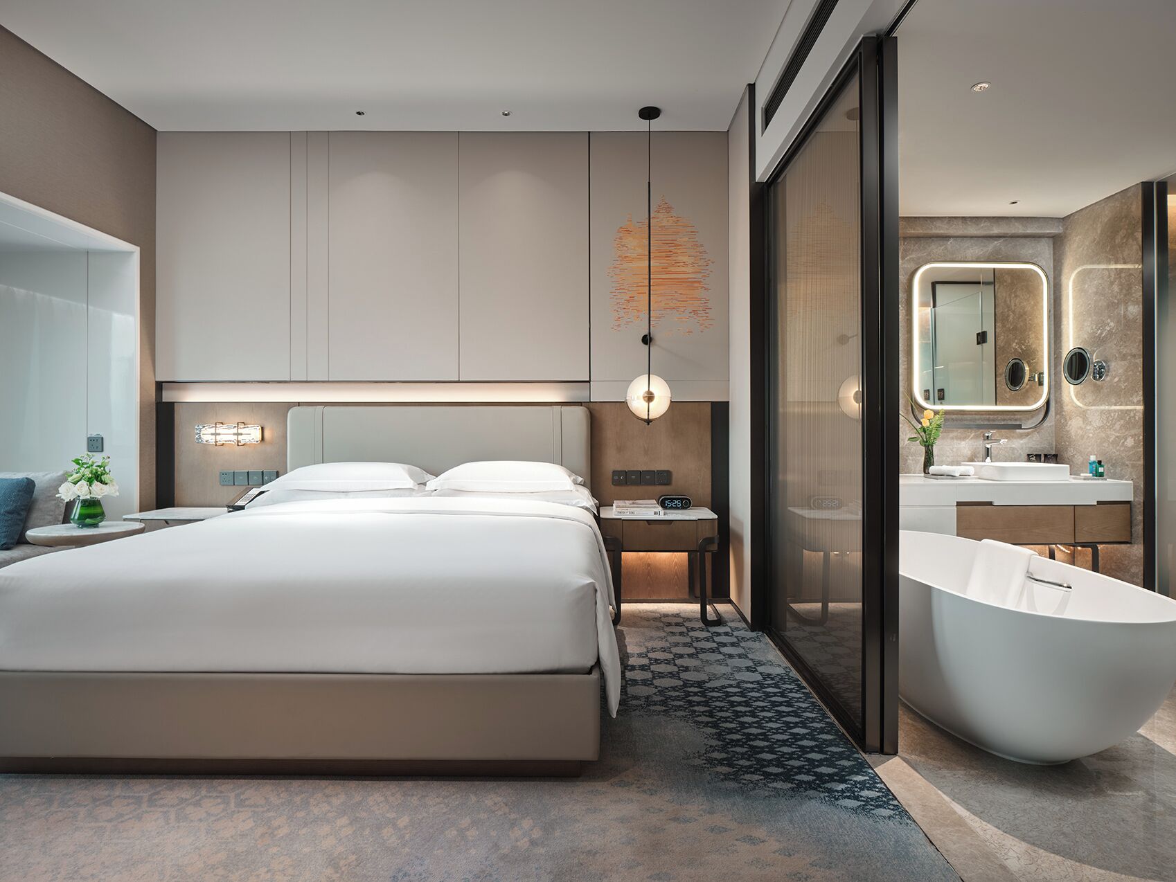 Une chambre d’hôtel moderne dotée d’un grand lit, d’une salle de bain séparée avec une baignoire sur pieds et d’un grand miroir.