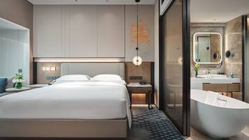 Une chambre d’hôtel moderne dotée d’un grand lit, d’une salle de bain séparée avec une baignoire sur pieds et d’un grand miroir.