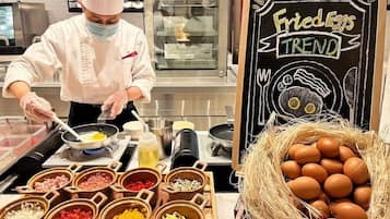 Un chef preparando comida en una cocina con diversos ingredientes y un letrero de pizarra que dice "Huevos Fritos en Tendencia".