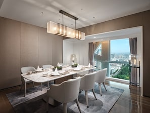 Un comedor moderno con una larga mesa dispuesta para seis personas, vistas a la ciudad y una lámpara de techo contemporánea.