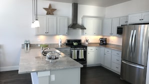 A modern kitchen with white cabinets, stainless steel appliances, and a granite countertop. - Bozeman Southside Retreat- 30+ Night Rental Home on Bozeman's South Side (Bozeman)