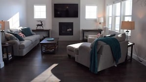 A modern living room with a fireplace, two sofas, a coffee table, and a TV mounted on the wall. - Bozeman Southside Retreat- 30+ Night Rental Home on Bozeman's South Side (Bozeman)