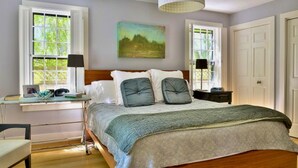 A bedroom with a bed, two bedside tables, a desk, and a chair.