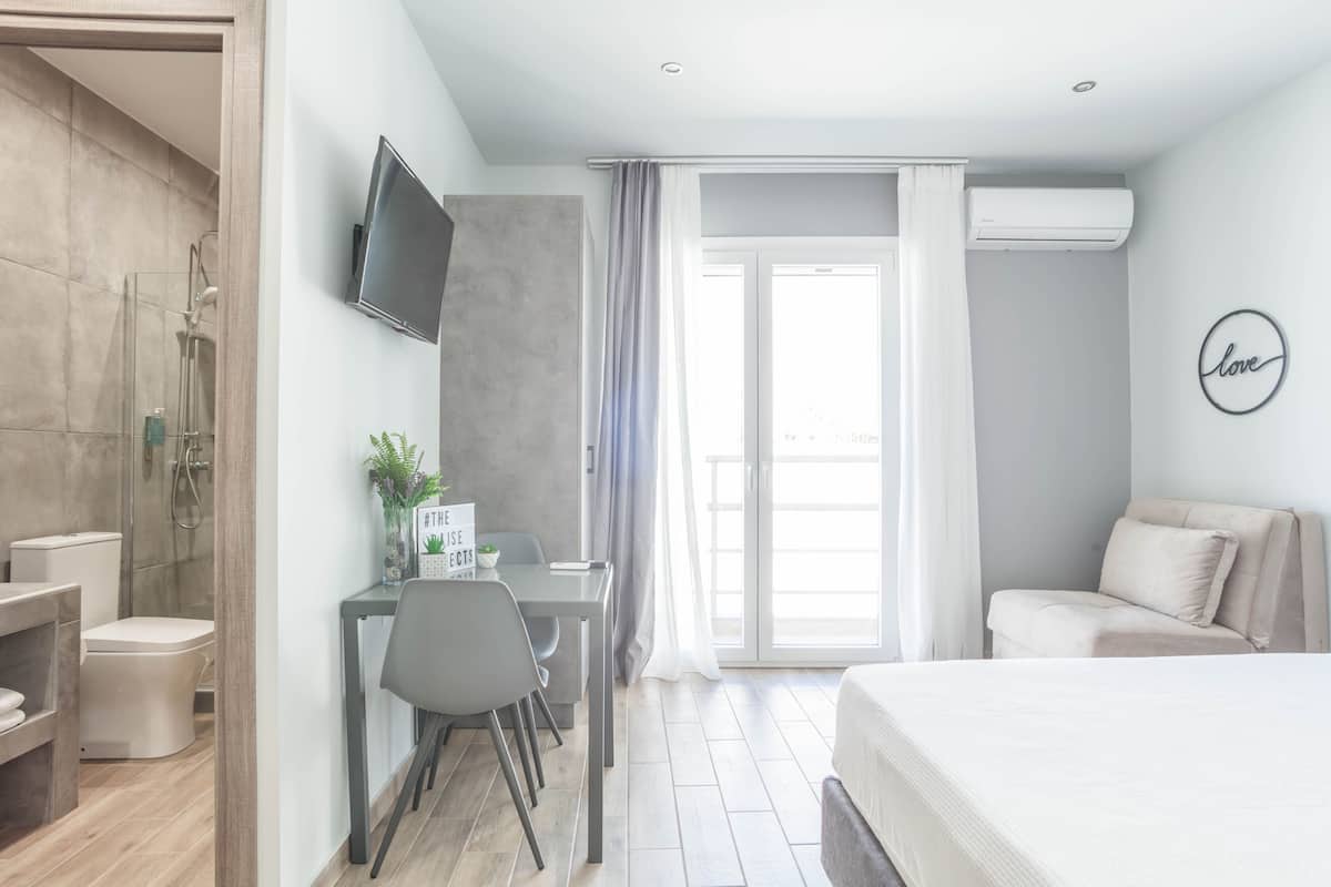 Une chambre d’hôtel moderne équipée d’une douche, de toilettes, d’un lit et d’un coin repas avec une table et des chaises.