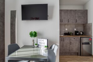 Une cuisine moderne avec des meubles gris, un four encastré et un réfrigérateur.