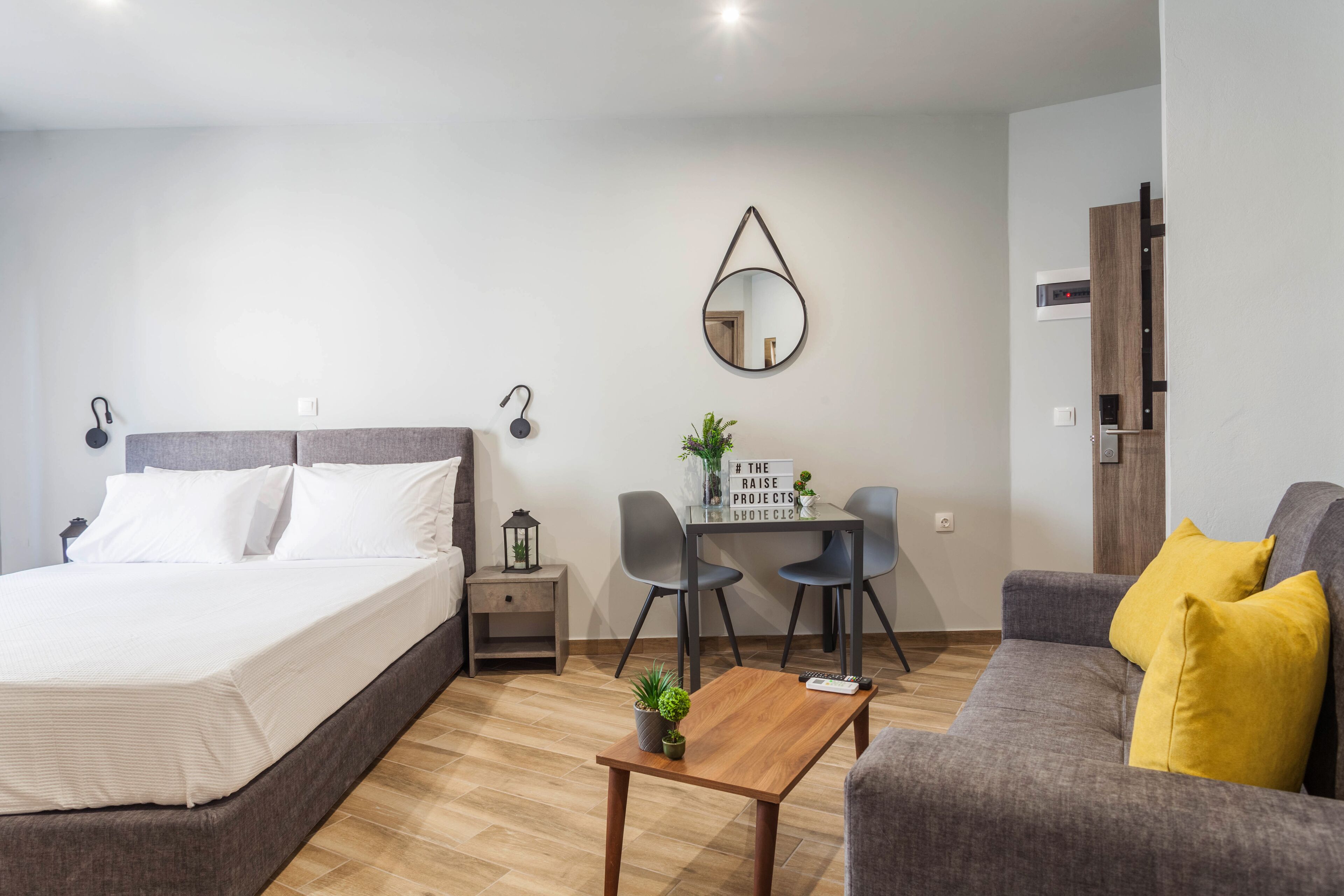 Un dormitorio moderno con cama, mesitas de noche, un escritorio y un sofá.