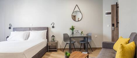 A modern bedroom with a bed, bedside tables, a desk, and a sofa.