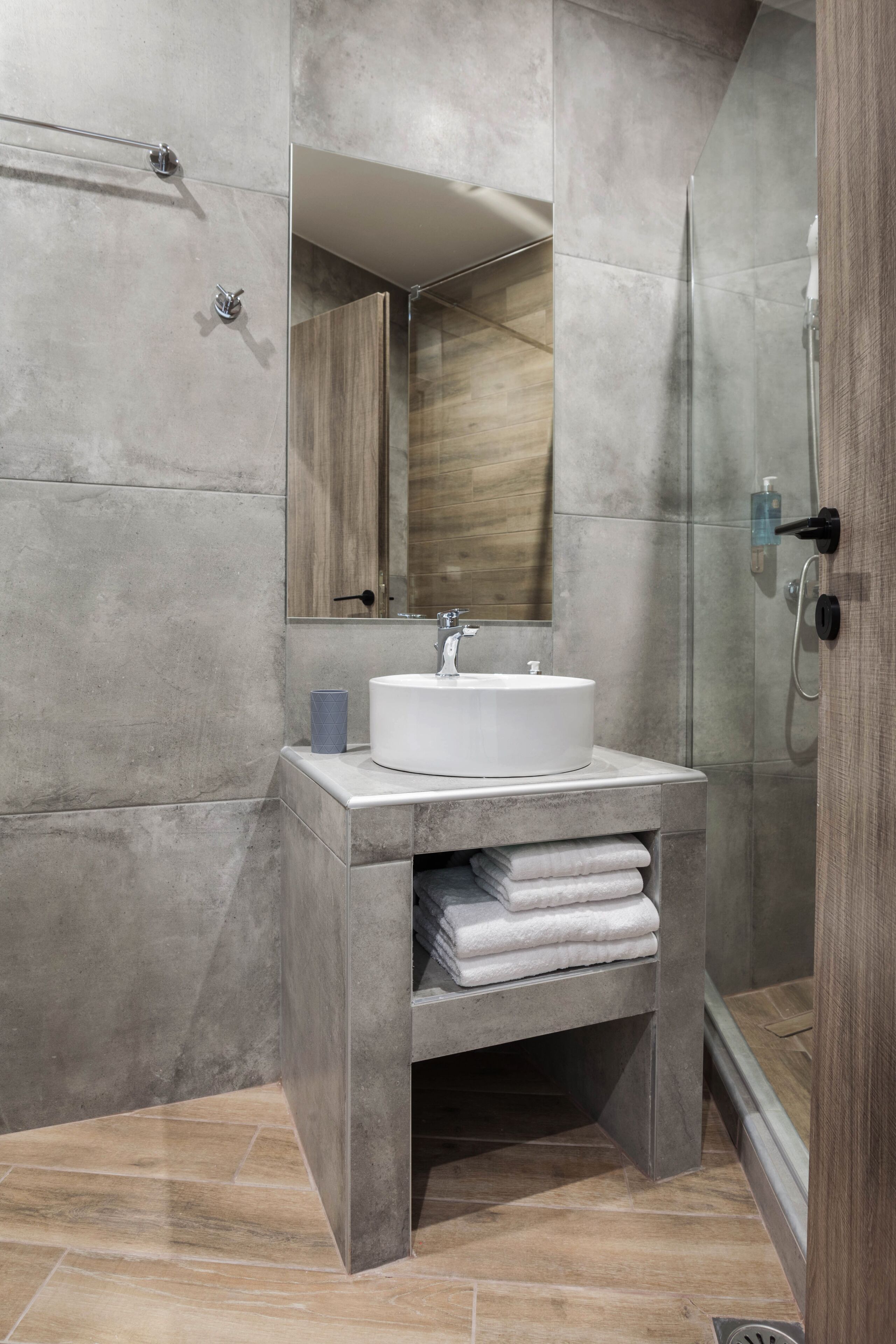 A modern bathroom with a large mirror, a white sink, and a glass shower enclosure.
