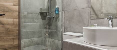 Een moderne badkamer met een douchecabine van glas, een wit toilet en een wastafel met spiegel erboven.