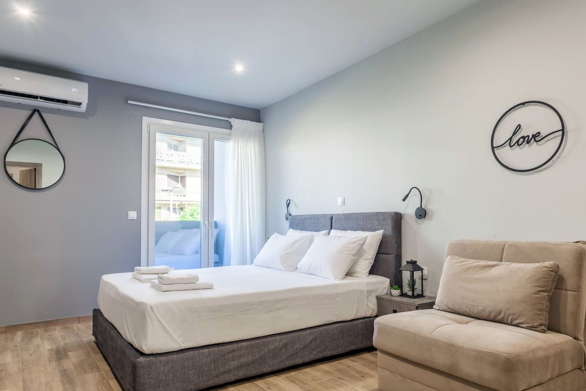 Une chambre moderne avec un lit, un canapé, un miroir et un climatiseur fixé au mur.