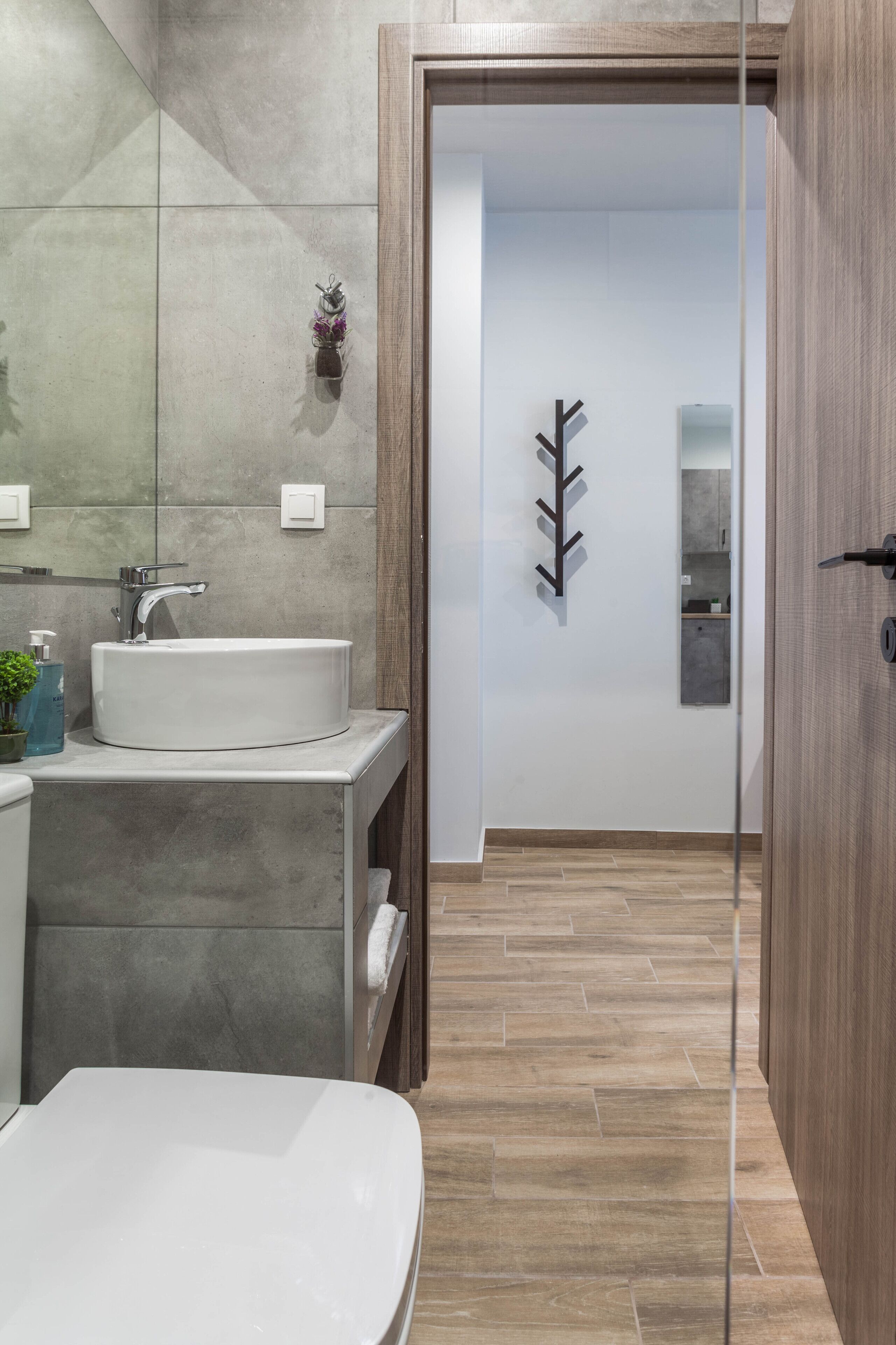 Un baño moderno con un lavamanos grande, un espejo y una puerta de madera que da a otra habitación.