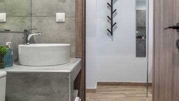 Un baño moderno con un lavamanos grande, un espejo y una puerta de madera que da a otra habitación.