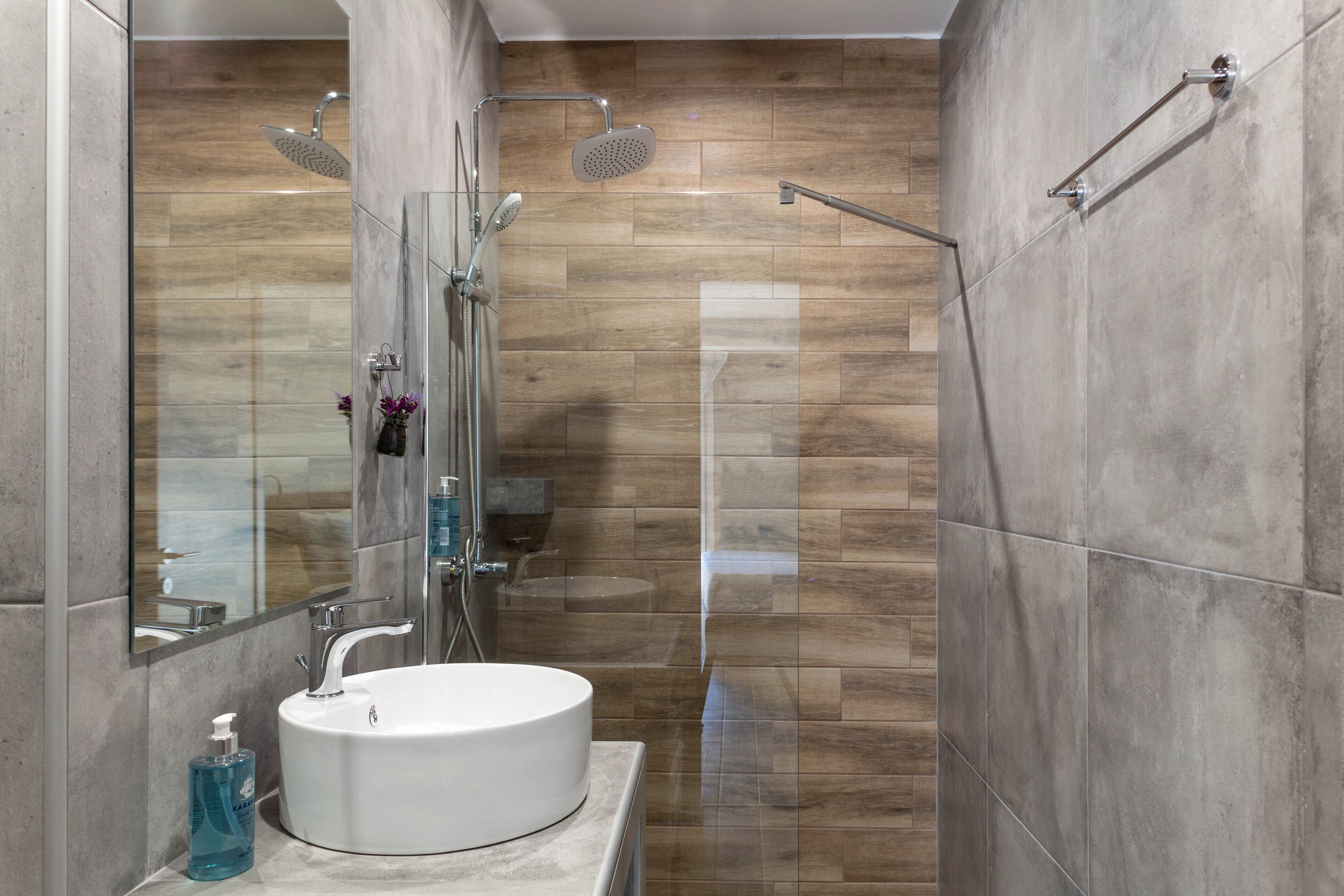 A modern bathroom with a round sink, a glass shower enclosure, and a large mirror.