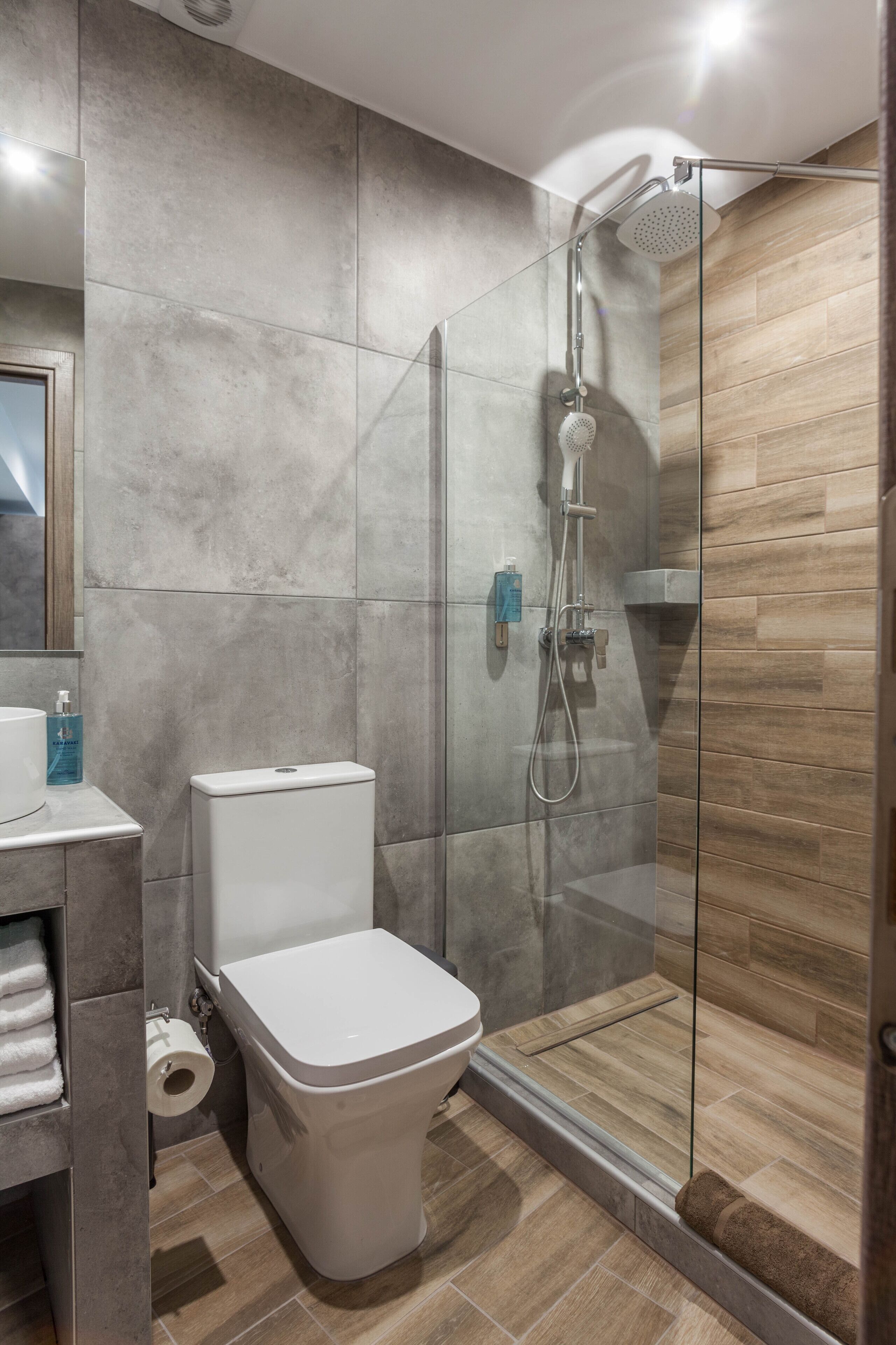 A modern bathroom with a glass-enclosed shower, a toilet, and a sink.