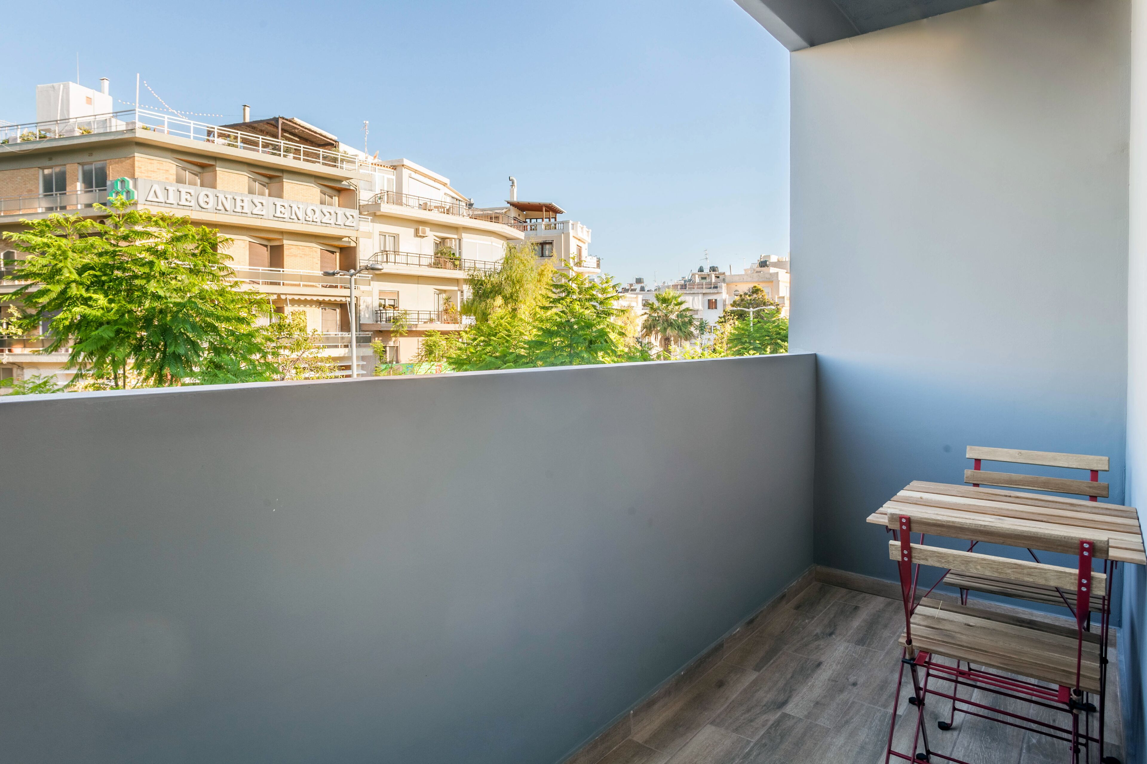 A balcony with a wooden bench and a metal table.