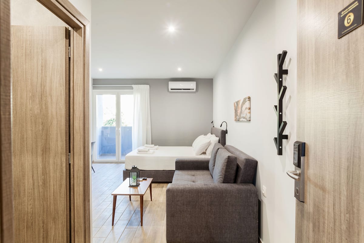 Une chambre d’hôtel moderne équipée d’un lit, d’un canapé, d’une petite table et d’un appareil de climatisation.