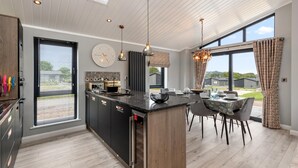 A modern kitchen with a central island, large windows, and a dining area with a view.