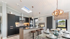 A modern kitchen with a central island, bar stools, and a dining area set for six.