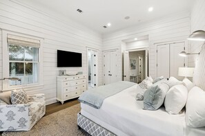 Ein Schlafzimmer mit einem großen Bett, einem Schminktisch, einem Fernseher und einem Fenster.
