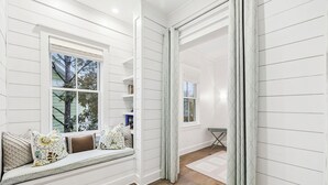 Ein Zimmer mit einer integrierten Sitzbank an einem Fenster, einem kleinen Tisch und einem gemusterten Vorhang.