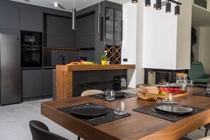 A modern kitchen with dark cabinetry, a wooden island, and a dining area set for a meal.
