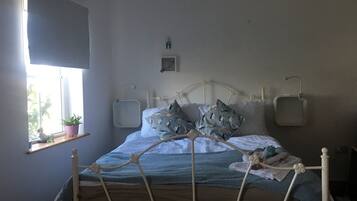 Un dormitorio con cama, ventana con planta y estante en la pared.