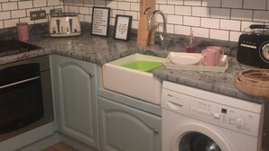 A kitchen with a sink, a toaster, a radio, and a washing machine. - Driftwood Loft (Downpatrick)