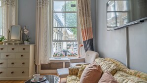 Un salon confortable avec un canapé, une table basse et une fenêtre donnant sur des immeubles.