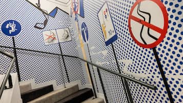 Una escalera con un muro a lunares y varios letreros de seguridad e indicación.