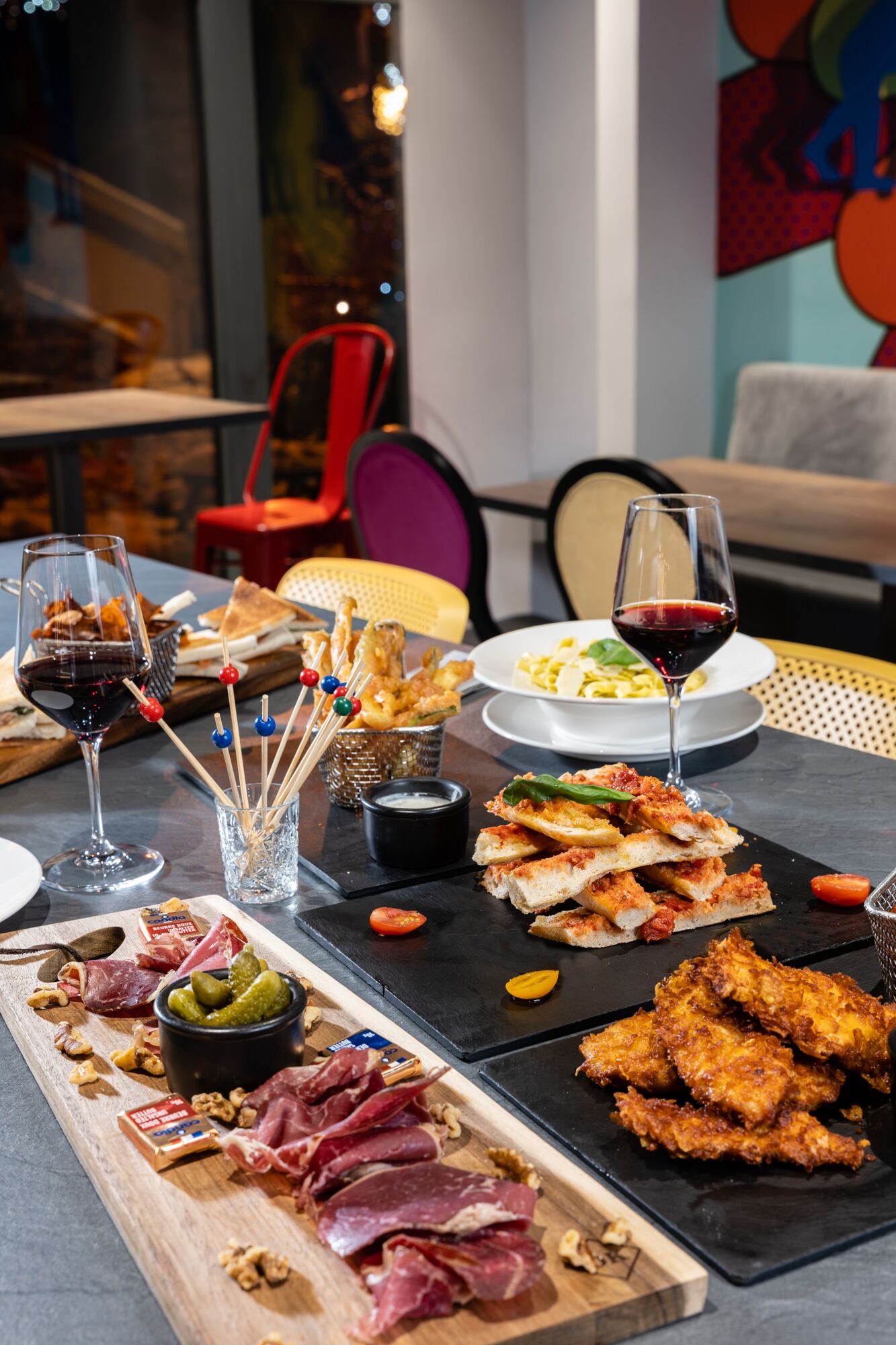Een eettafel met diverse gerechten, drankjes en een vleeswarenbord.