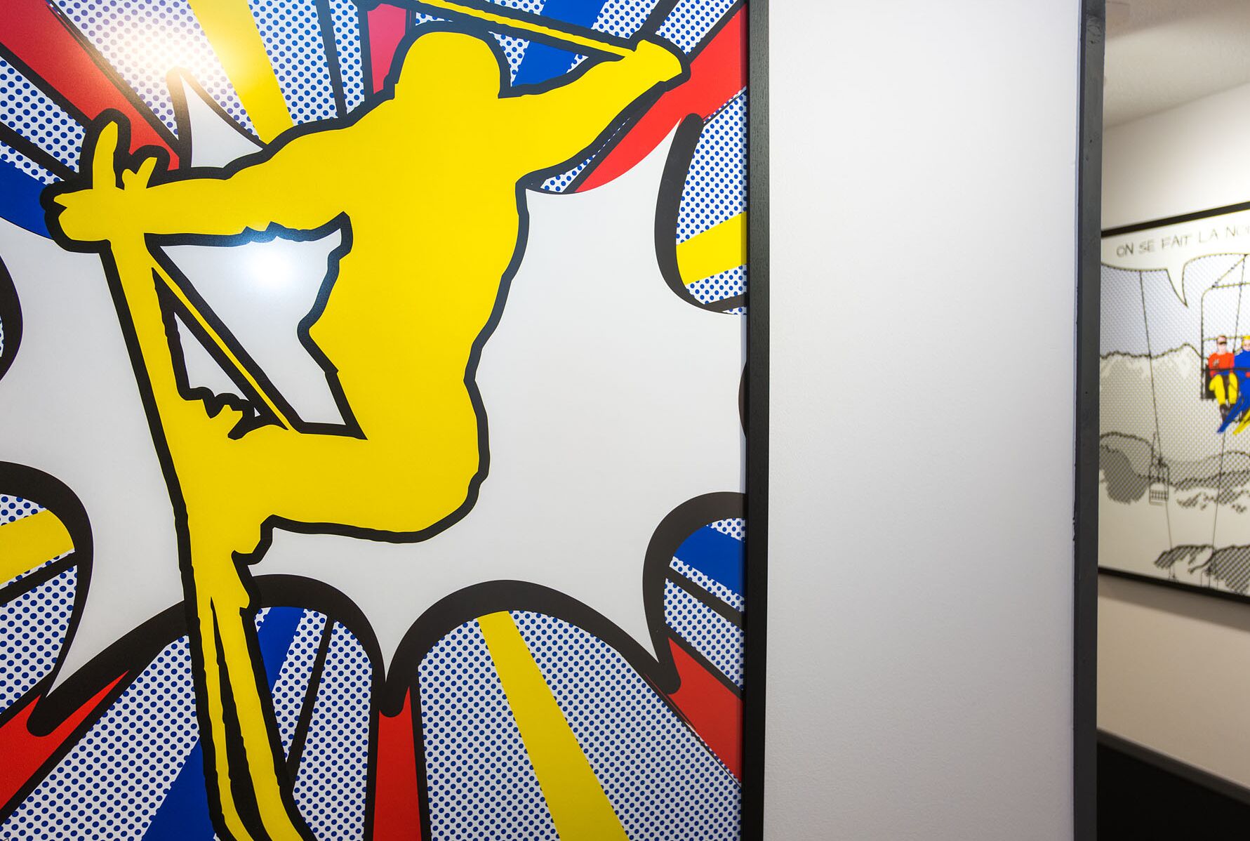 A wall with a large, stylized yellow figure holding a bow and arrow, surrounded by blue and red patterns.