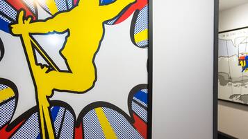 A wall with a large, stylized yellow figure holding a bow and arrow, surrounded by blue and red patterns.