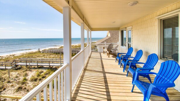 A covered deck with blue chairs, a wooden railing, and a view of the beach and ocean. - ☀️Next Time Down: Oceanfront Home w/ Deck-Private Beach Access☀️ (Kure Beach)