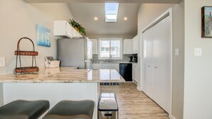 A modern kitchen with a central island, white cabinetry, and a view to the dining area. - ☀️Next Time Down: Oceanfront Home w/ Deck-Private Beach Access☀️ (Kure Beach)