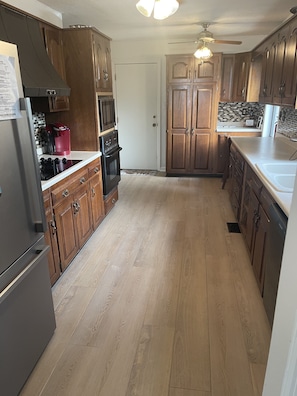 A kitchen with wooden cabinets, a stainless steel refrigerator, a microwave, a coffee maker, and a dishwasher.