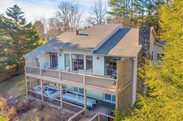 A two-story house with a balcony on the upper floor, surrounded by trees.