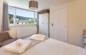 A bedroom with a bed, a radiator, a window with a view, a wardrobe, and a door. - The Dog House, Porlock (Porlock)