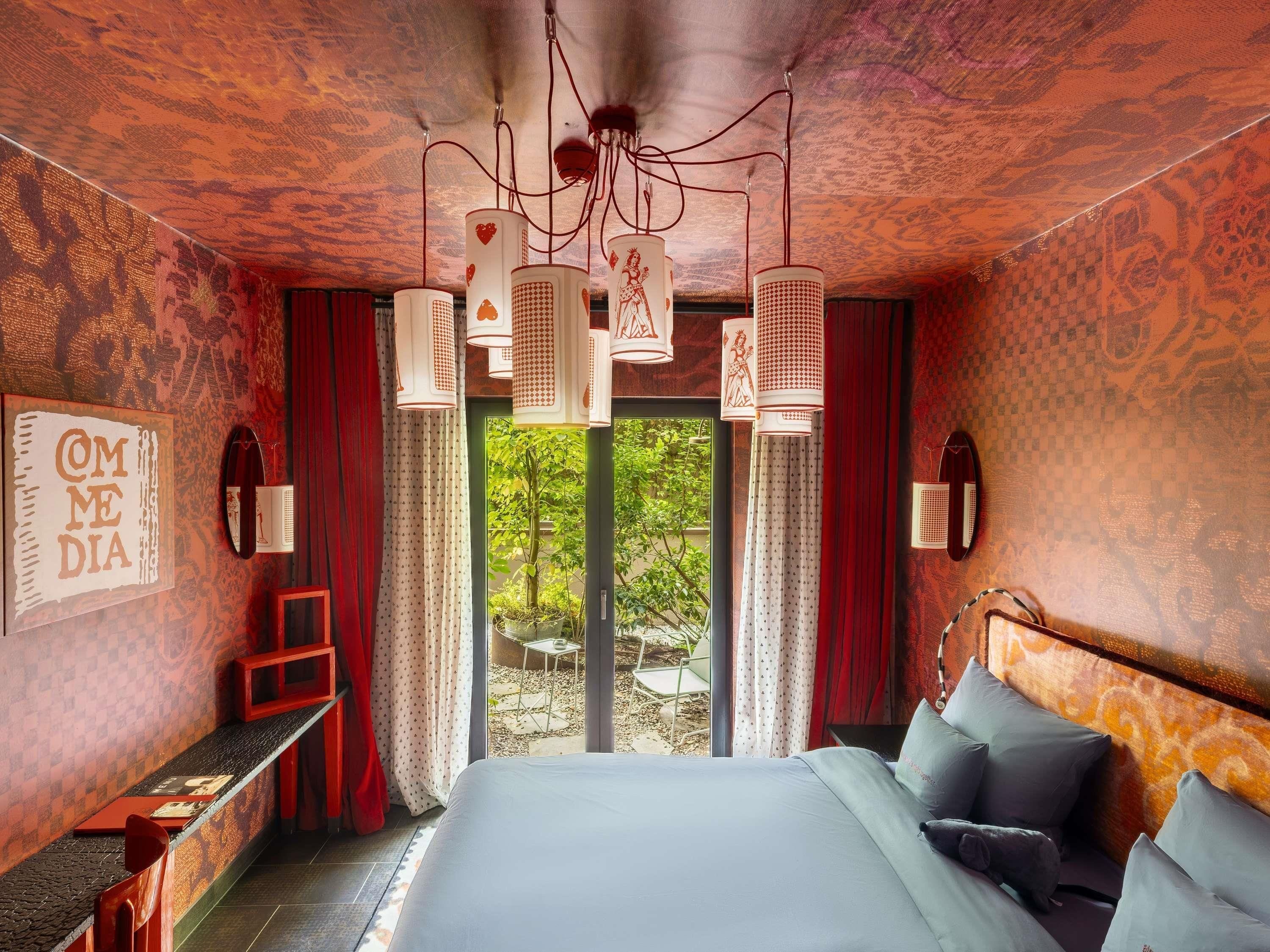 A bedroom with a large bed, a desk, and a view of greenery outside.