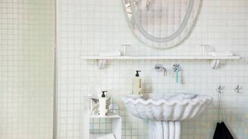 Un baño con lavamanos de mármol, un espejo y un perchero para toallas.