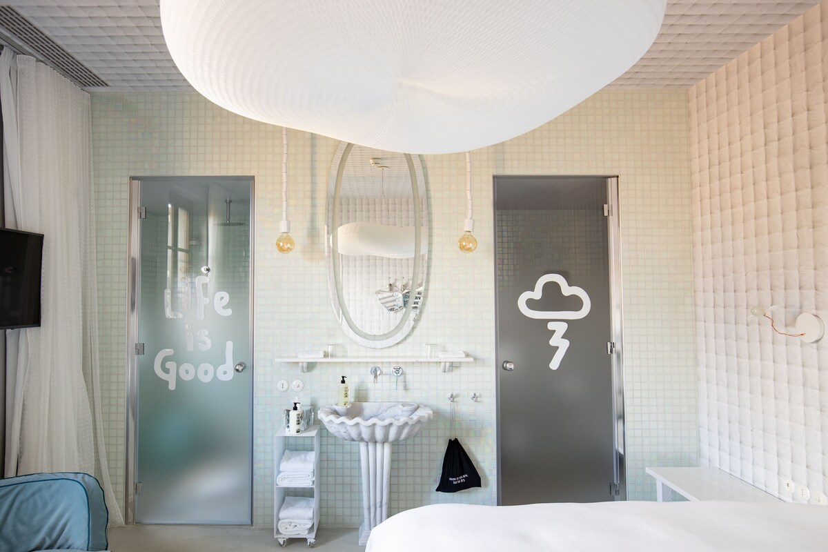 A modern bathroom with a large mirror, a white sink, and a shower area.