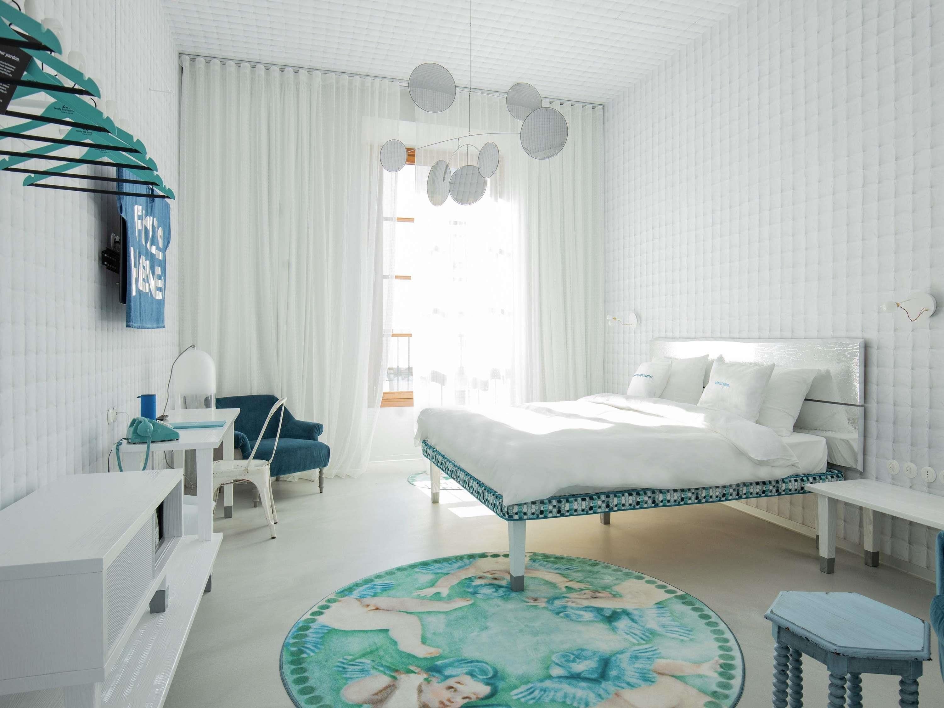 Een moderne slaapkamer met een bed, een bureau, een stoel en een rond vloerkleed.