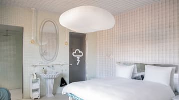 Un dormitorio moderno con una cama grande, un espejo redondo, un lavabo blanco y una puerta con un símbolo de clima.