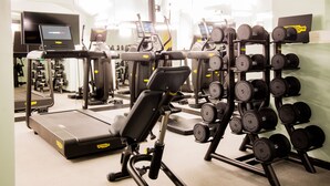 Een fitnessruimte met loopbanden, elliptische trainers en een rek met gewichten.